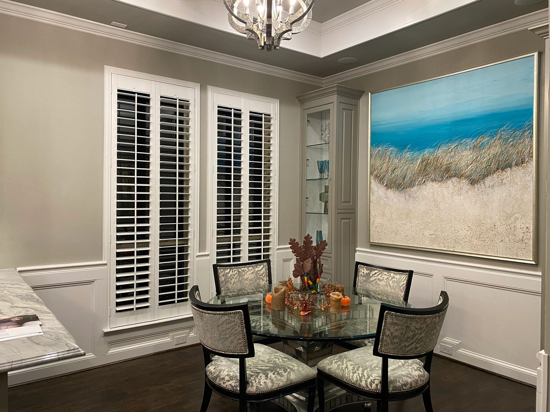 Dining room with arched shutters and coastal-themed artwork
